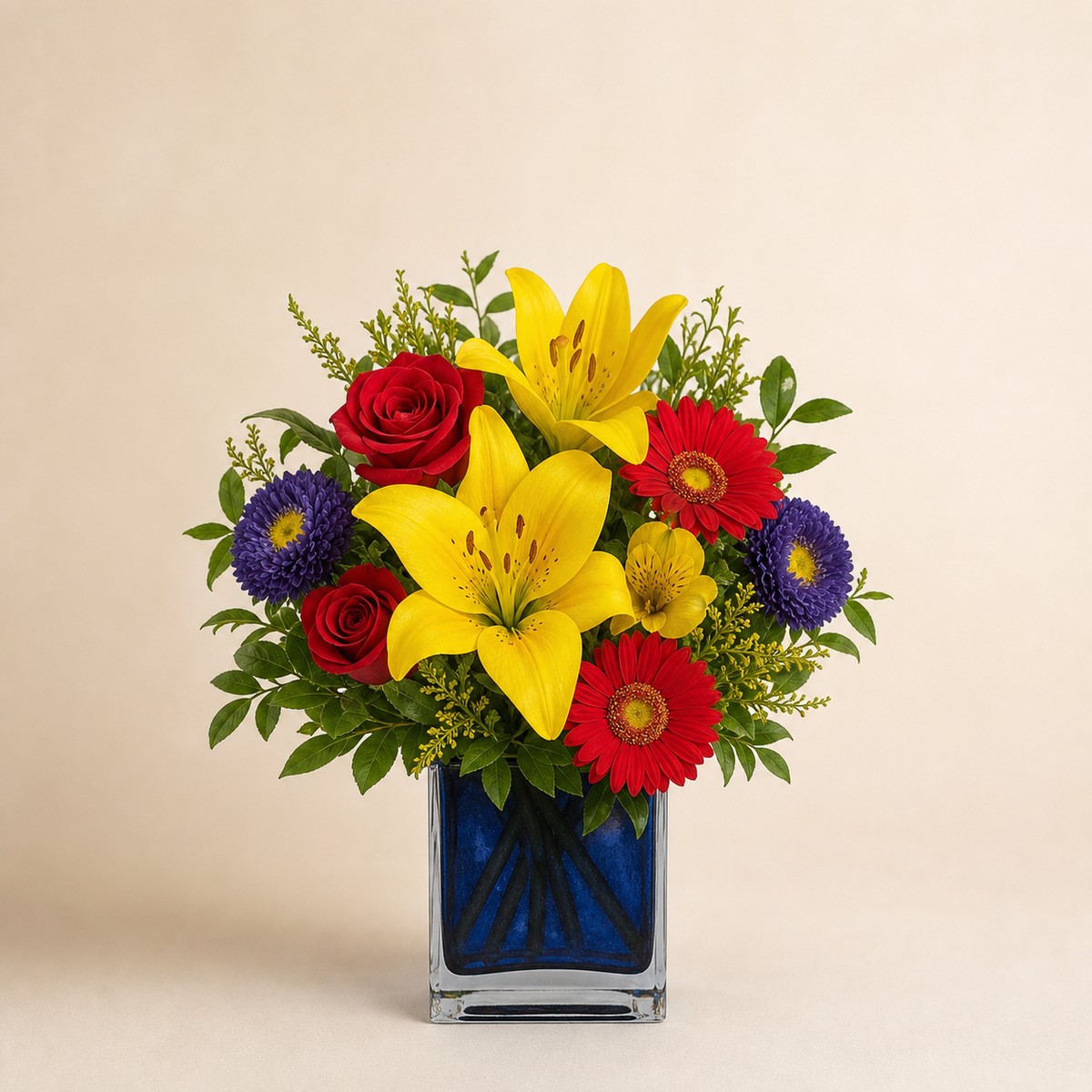 Caribbean Delight smaller Standard yellow lily, red rose, red gerbera and purple aster fresh flower arrangement in a clear rectangular vase with cobalt-blue liner