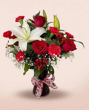 Crimson Devotion — red roses and white lilies in a dark vase with a red ribbon