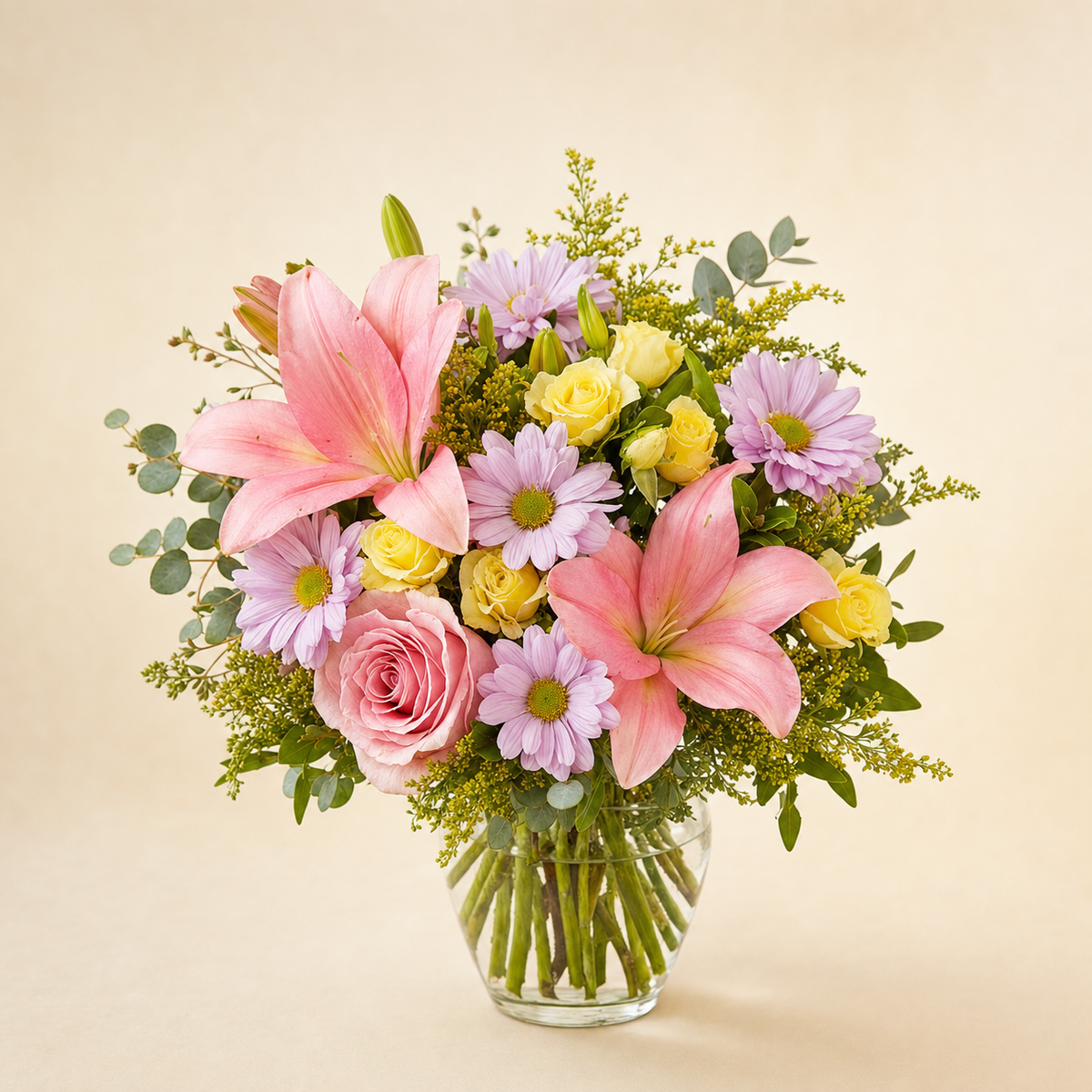 Blooming Elegance Standard – compact arrangement of pink lilies, pink rose, lavender daisies, yellow daisies and yellow spray roses in a clear glass vase, smaller lighter version