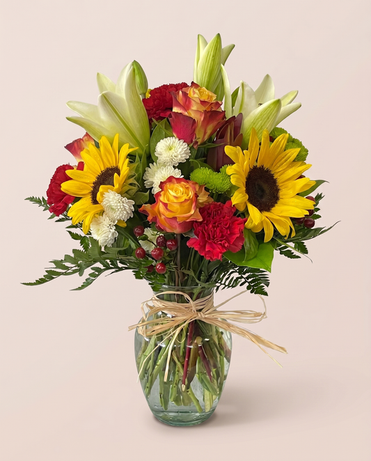 Sunlit Harvest Bouquet — sunflowers, roses, lilies, and carnations in a glass vase