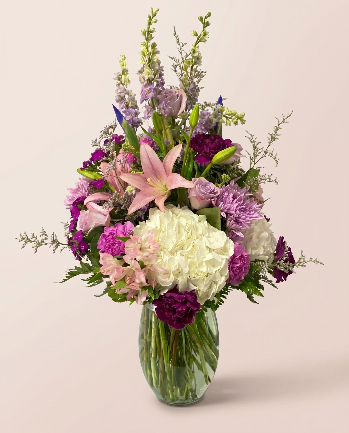 Plum Blossom Medley — pink, purple, and white blooms in a glass vase