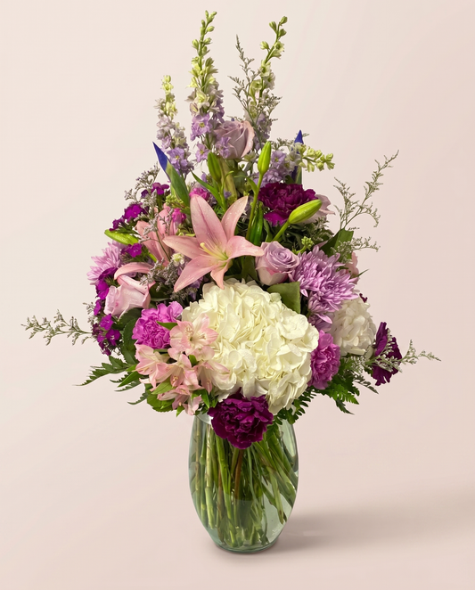 Plum Blossom Medley — pink, purple, and white blooms in a glass vase