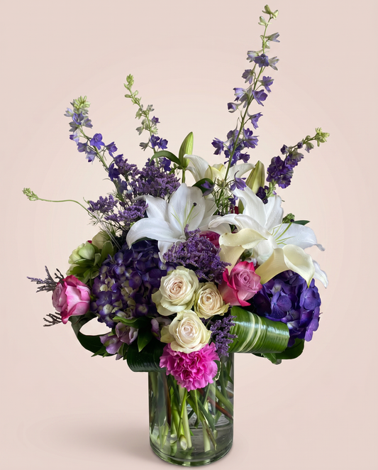 Twilight Lily Bouquet — white lilies, purple delphinium, and pink roses in a glass vase