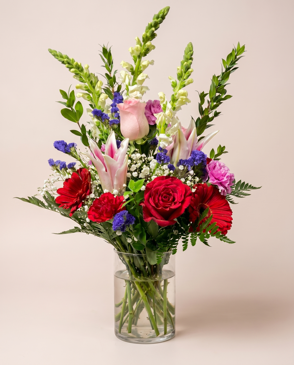 Coral Whisper Bouquet — coral and pink roses with gerbera daisies in a glass vase